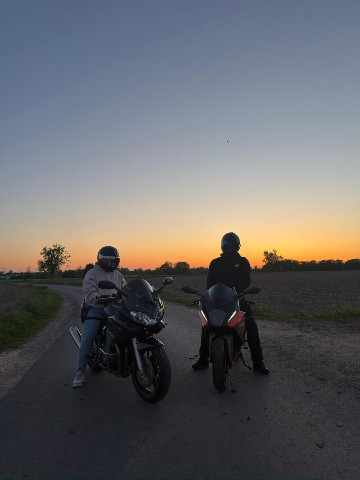Zwei Fahrer mit ihren Motorrädern bei Sonnenuntergang